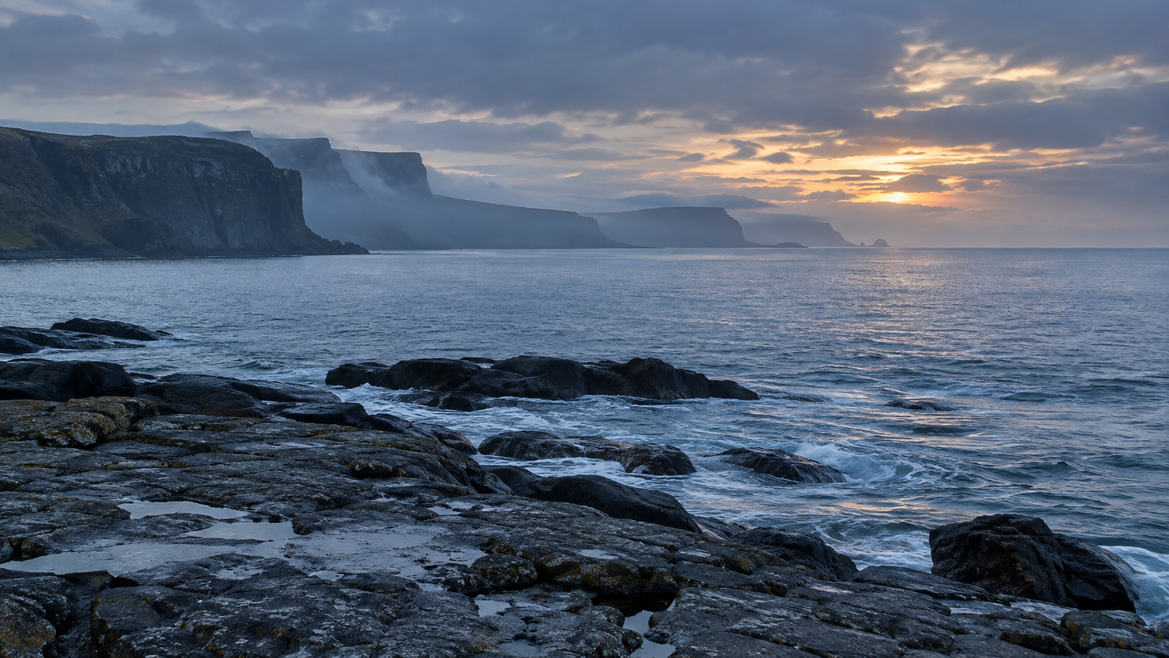 Rocky shoreline beneath layered sea cliffs at blue hour